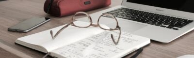 eyeglasses on book beside laptop